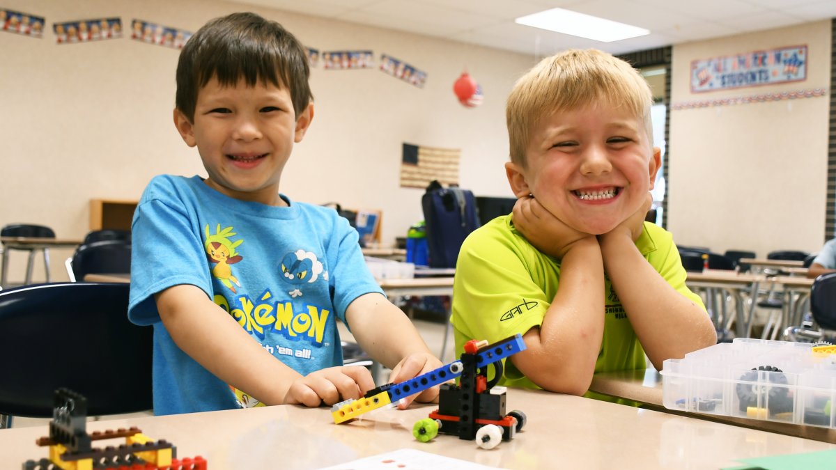 Two students smile while working with Legos at a desk