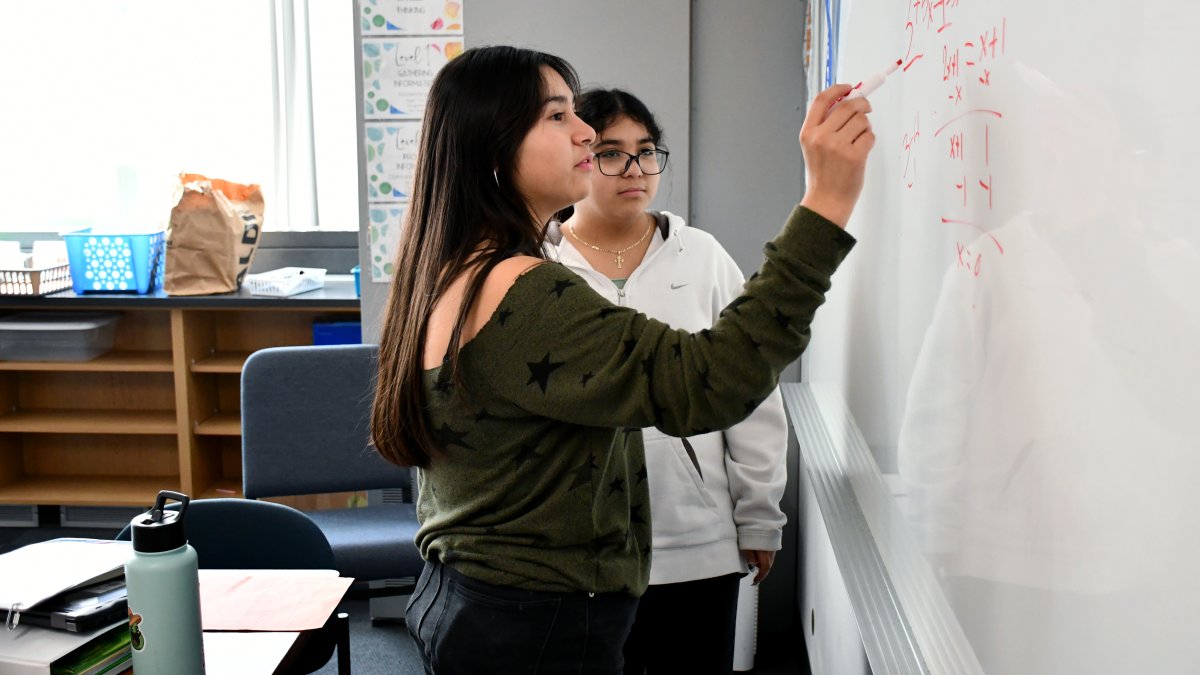 two students writing on whiteboard
