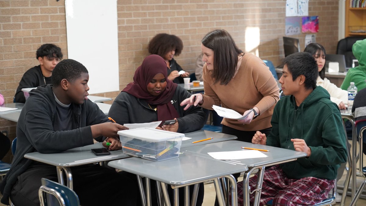 teacher talking to three students at table